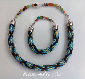 Conjunto de collar y pulsera flor azul y fondo negro, con abalorios de cristal de colores y terminales y cierres plateados. 